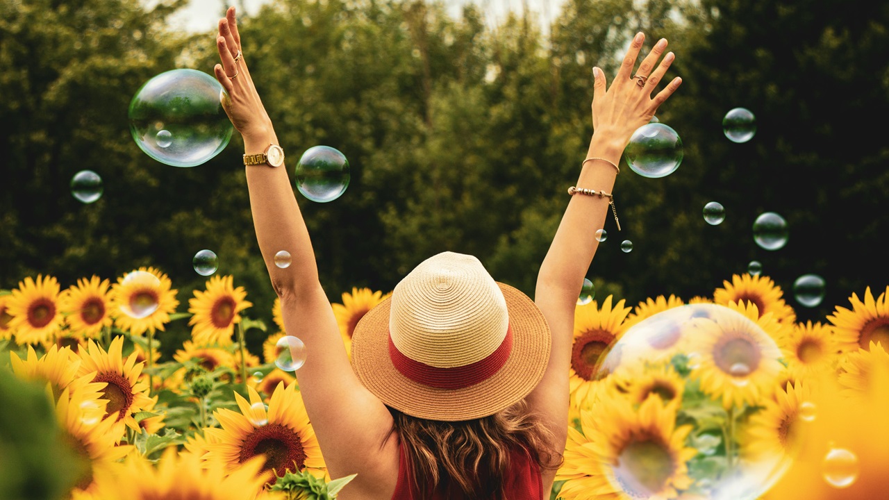 A happy woman in a sunflower field.